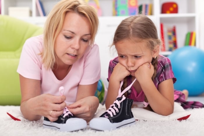 мама учит ребенка завязывать шнурки
