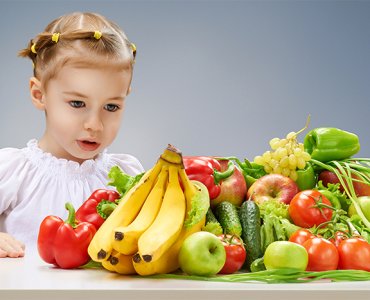 девочка за столом с овощами и фруктами