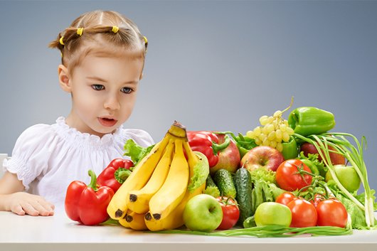 девочка за столом с овощами и фруктами