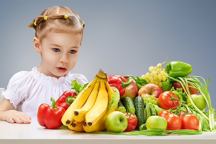 девочка за столом с овощами и фруктами 