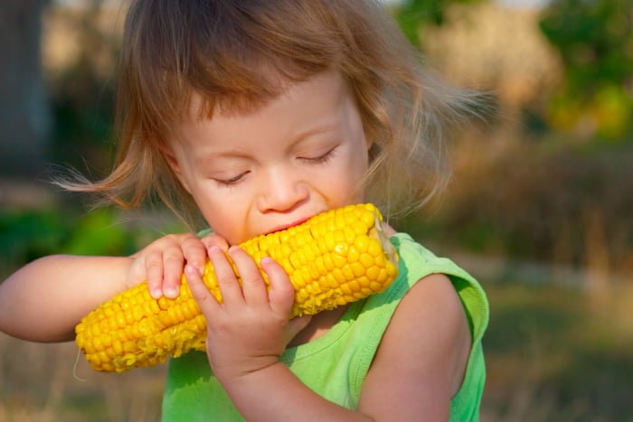 Девочка ест кукурузу