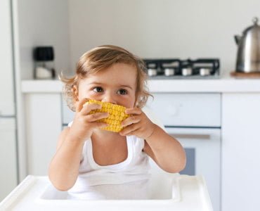 Ребенок ест кукурузу вареную