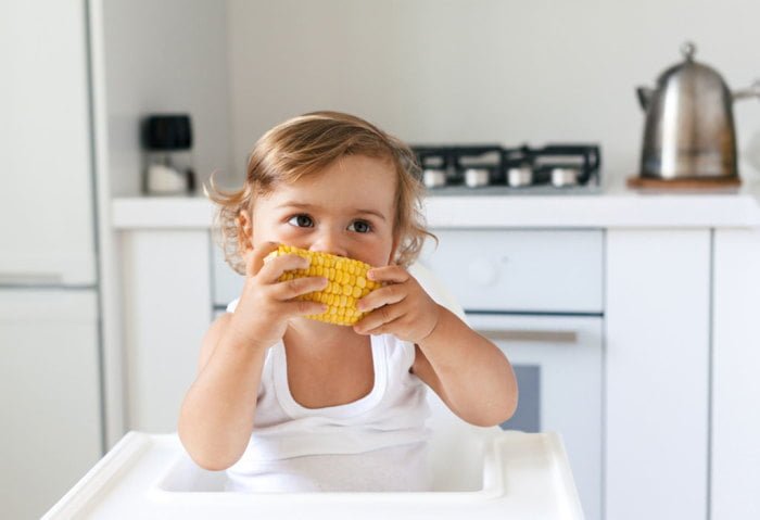 Ребенок ест кукурузу вареную