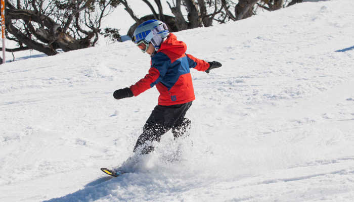 Ребенок учится кататься на сноуборде